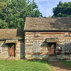 A log cabin with two doors and a porch.