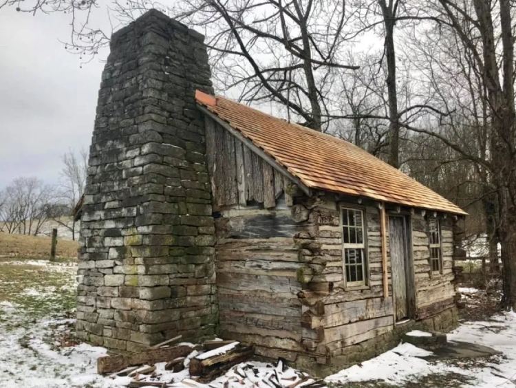 A log cabin with a brick chimney in the middle of it.